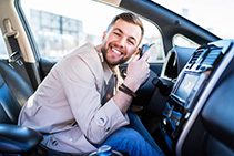 Satisfied man loves his car. Positive driver lies on the steering wheel of the auto