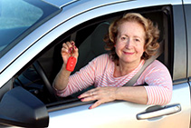 Cute mature female driver holding car keys.
