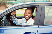 Closeup portrait happy, smiling, young man, buyer sitting in his new blue car showing keys isolated outside dealer, dealership lot. Personal transportation, auto purchase concept